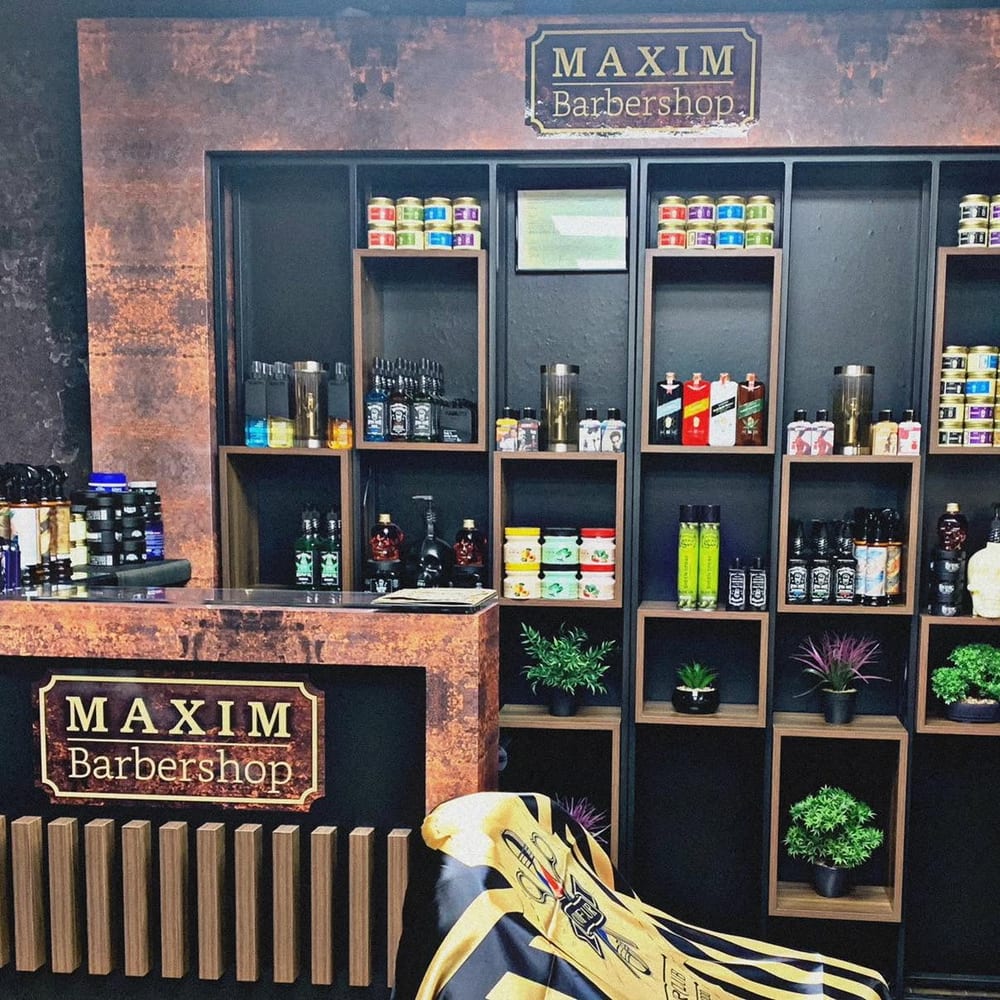 Tresen und Produktwand im Laden, darüber das Schild MAXIM Barbershop